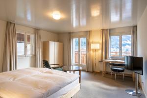 翁根Hotel Alpenruhe - Vintage Design Hotel的一间卧室配有一张床、一张书桌和一台电视