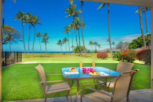 基黑Gorgeous Oceanfront Condo with Spectacular Views!的棕榈树草坪上的蓝色桌子和食物