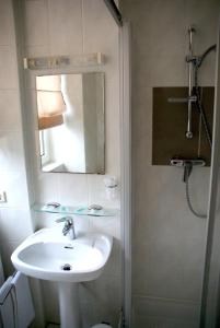 Senningerberg查理火车站旅馆的浴室配有盥洗盆和带镜子的淋浴