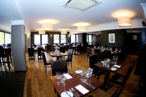 威廉堡尼维斯河畔旅馆的餐厅设有木桌、椅子和窗户。