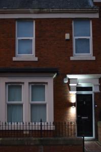 泰恩河畔纽卡斯尔9 bed house (7 Mins) 2 miles from Newcastle centre的砖屋,有黑色的门和窗户