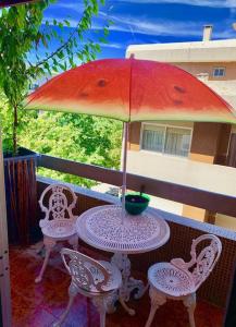 马亚Coffee Cream Guest House Maia的阳台配有桌椅和遮阳伞