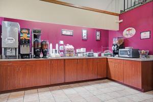 罗杰斯Super 8 by Wyndham Rogers Minnesota的一间设有柜台和粉红色墙壁的餐厅