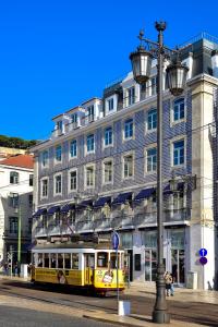 里斯本My Story Hotel Figueira的大型建筑前的黄色电车