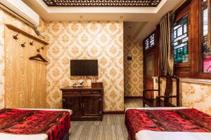 平遥Pingyao Hongyuyuan Guesthouse的一间卧室设有两张床,墙上配有电视。