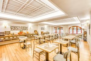 毕尔巴鄂Sercotel Arenal Bilbao的餐厅铺有木地板,配有桌椅