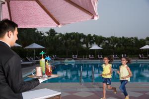 新德里新德里泰姬陵酒店的一个人在游泳池前和两个孩子说话