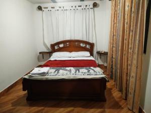 波帕扬Green Hostal Popayan的一间卧室配有一张带木制床头板和窗帘的床。