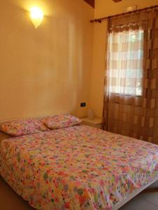 TeoloAgriturismo Ca Noale的一间卧室配有一张带花卉床罩的床和窗户。