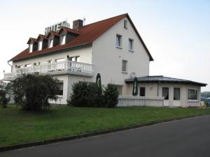 Knüllwald林登酒店的一座大型白色房屋,设有红色屋顶