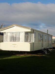 拉尔Lovely 4 berth static caravan, Marine Holiday Park, Rhyl, Wales的移动房屋停放在庭院内