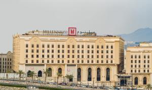 麦加Millennium Makkah Al Naseem的一座大型建筑,前面有汽车停放