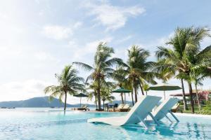瓜埠兰卡威海洋居酒店的一个带椅子和棕榈树的游泳池以及大海