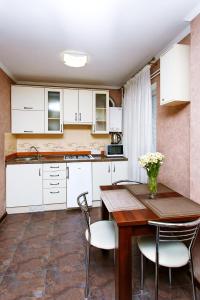 切尔尼戈夫Comfortable apartment in the center的厨房配有白色橱柜和木桌及椅子