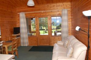 基林Cosy Rowan woodland lodge no1的木制客厅设有白色沙发