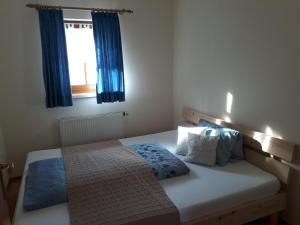 瓦格赖恩奥伯霍夫公寓的一间卧室配有一张带蓝色窗帘的床和一扇窗户