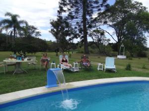 梅洛埃斯坦西亚罗萨里奥农家乐的一群人坐在游泳池旁的草坪椅上