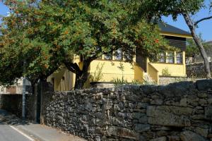 佩尼亚什达绍迪Casa da Serra的黄色房子前面的石墙和树木