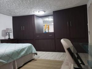 金斯敦Hill Retreat - Kingston的一间卧室配有木制橱柜、一张床和一把椅子