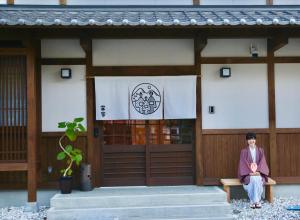 下吕市寅家 Japanese modern hotel的坐在大楼前长凳上的女人