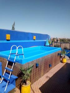 马拉喀什真纳庭院旅馆的蓝色游泳池,在砖墙旁边设有梯子