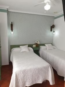 阿维拉唐迭戈旅馆的一间卧室配有两张带白色床单和墙壁的床。