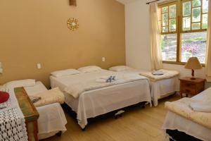 圣若昂-达巴拉Rancho Hollywood - Lago de Furnas的一间卧室设有三张床和窗户。