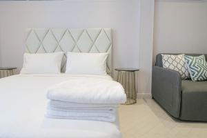新加坡Comfy Studio 7 by ReCharge的卧室配有白色床、椅子和枕头