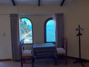 Isla de SolJACHA INTI的一间设有两把椅子和两个大窗户的房间