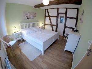 措伊伦罗达Zur alten Schäferei的卧室配有白色的床,铺有木地板
