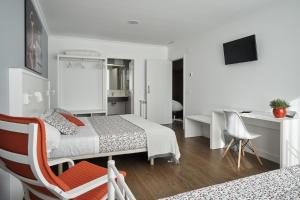 AbadínXabarin Rooms的白色卧室配有床、书桌和椅子