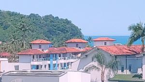 乌巴图巴Apto Ubatuba Praia Grande - 4 quartos - piscina privativa的一座白色的大建筑,有红色的屋顶