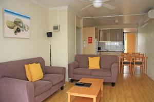 麦夸里港水景公寓的客厅配有两张沙发和一张桌子