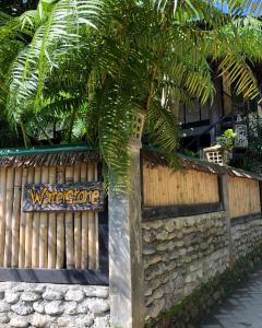武吉拉旺Waterstone Guesthouse的树旁有欢迎标志的栅栏