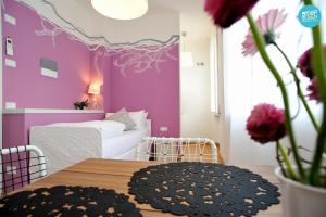 乌迪内乌迪内民事医院前留宿旅馆的卧室设有紫色墙壁、桌子和床。