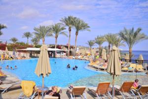 沙姆沙伊赫卡塔海风度假村的度假村的游泳池,里面配有椅子和遮阳伞