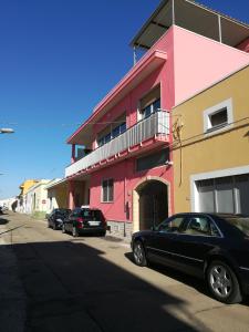 蒂贾诺La Baronessa的一座粉红色的建筑,前面有汽车停放