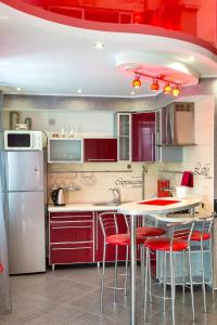 尼古拉耶夫Люкс студия 1 комнатная,в центральном районе города的厨房配有红色橱柜和一张带红色椅子的桌子