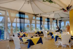 利多迪耶索罗拿破仑酒店的餐厅设有桌子和白色的椅子以及窗户。