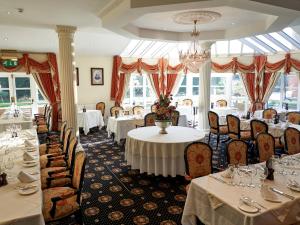锡廷伯恩赫普斯特德之家餐厅酒店的一间带桌椅和吊灯的餐厅