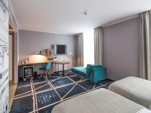 波兹南波兹南中心美居酒店的酒店客房,设有两张床和一张蓝色椅子