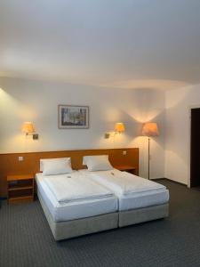 美因河畔法兰克福Hotel Mondial Comfort - Frankfurt City Centre的一间卧室配有一张大床和两盏灯