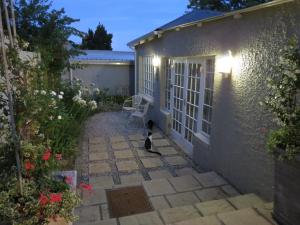 格拉罕镇AppleBee Guest Cottages的坐在房子前面的庭院里的猫