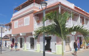 圣玛丽亚Hotel MiraBela的一座粉红色的建筑,前面有一棵棕榈树