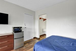 橘园Zen Living Suites Extended Stay - Jacksonville - Orange Park的一间卧室配有一张床,并在柜台上配有电视