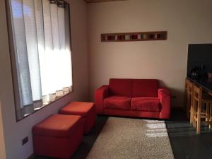 普孔Loft Pucon的客厅配有红色的沙发和凳子