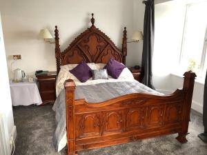林顿北崖酒店的一间卧室配有一张带紫色枕头的大木床