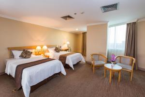 花都广州新世纪酒店的酒店客房带两张床和一张桌子以及椅子。