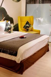 怡保Sojourn Spa Hotel Ipoh的一间卧室配有一张带黄椅的床