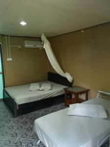 刁曼岛Puteri Salang Inn的一间设有两张床和一张桌子的房间